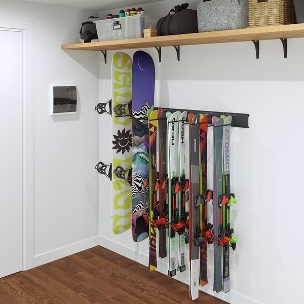 Ski og snowboard hengt ryddig på veggskinner i en bod